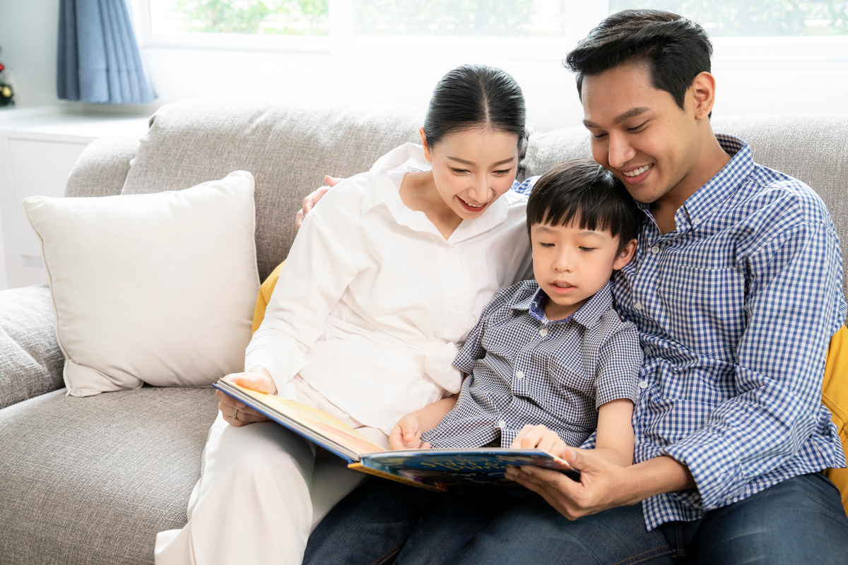 Asian Parents With Child Reading Story Indoors